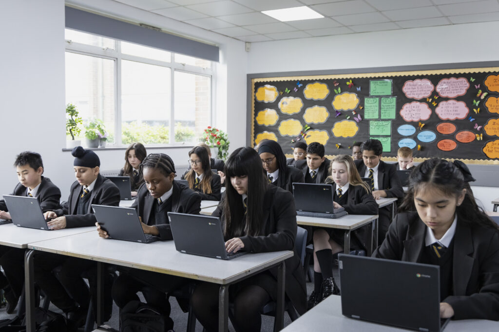 Rows of students sat at desks working on laptops