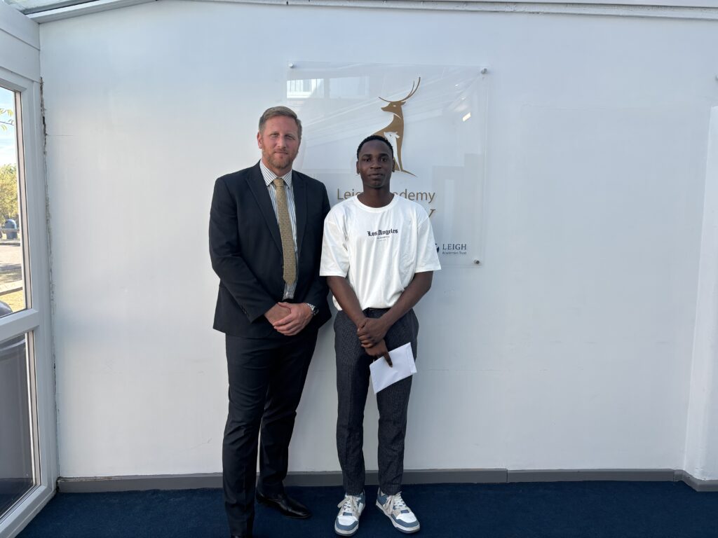 A male Post-16 student is pictured smiling for the camera alongside his Principal, after having just opened his A-Level results.