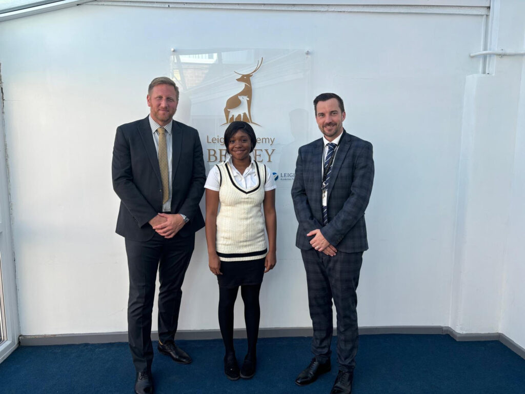 A female Post-16 student is pictured smiling for the camera alongside three members of staff, after having just opened her A-Level results.