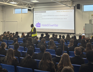 A teacher presents "Read & Write" software to students in an assembly.